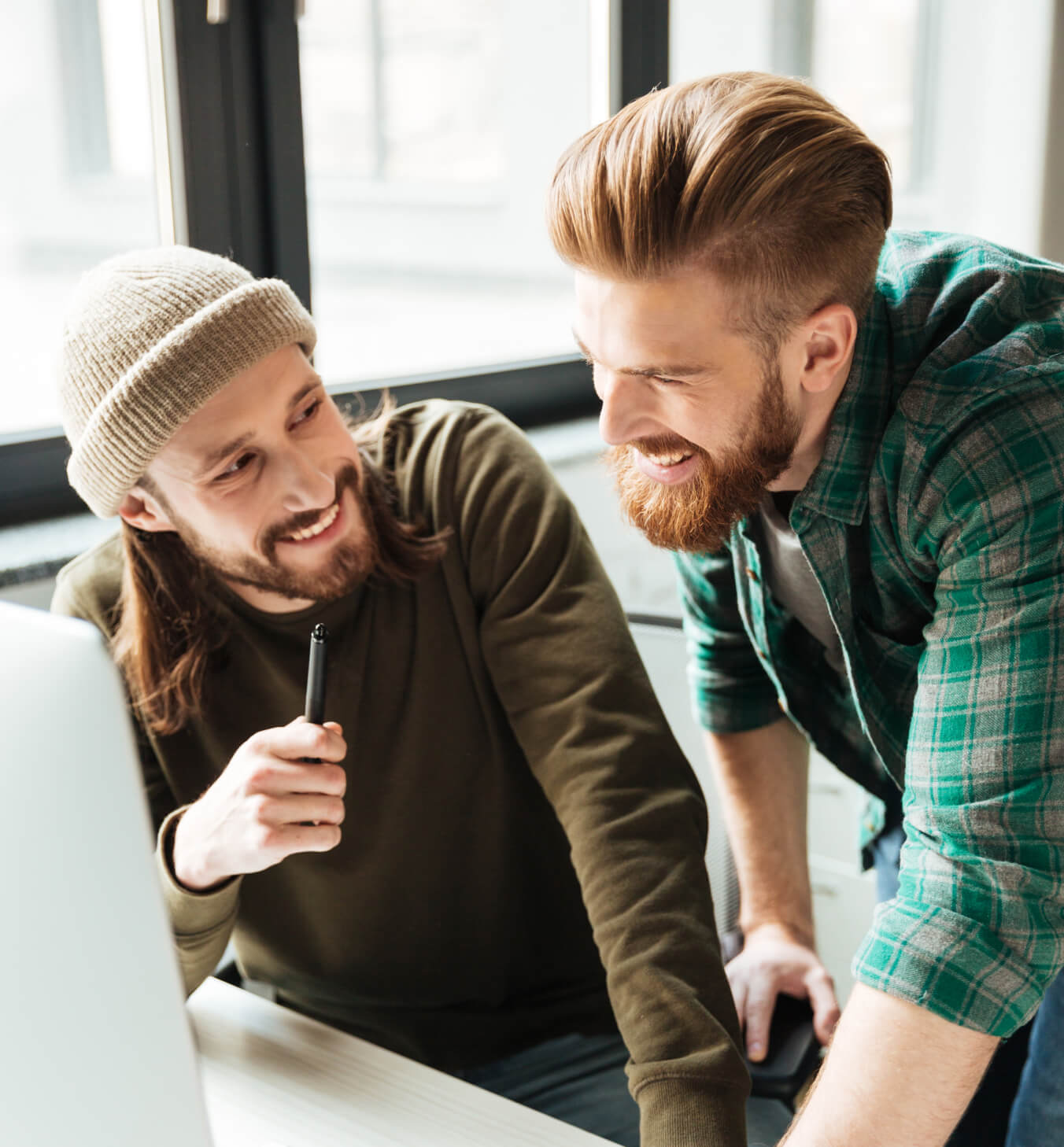 Two men are looking at a laptop screen.